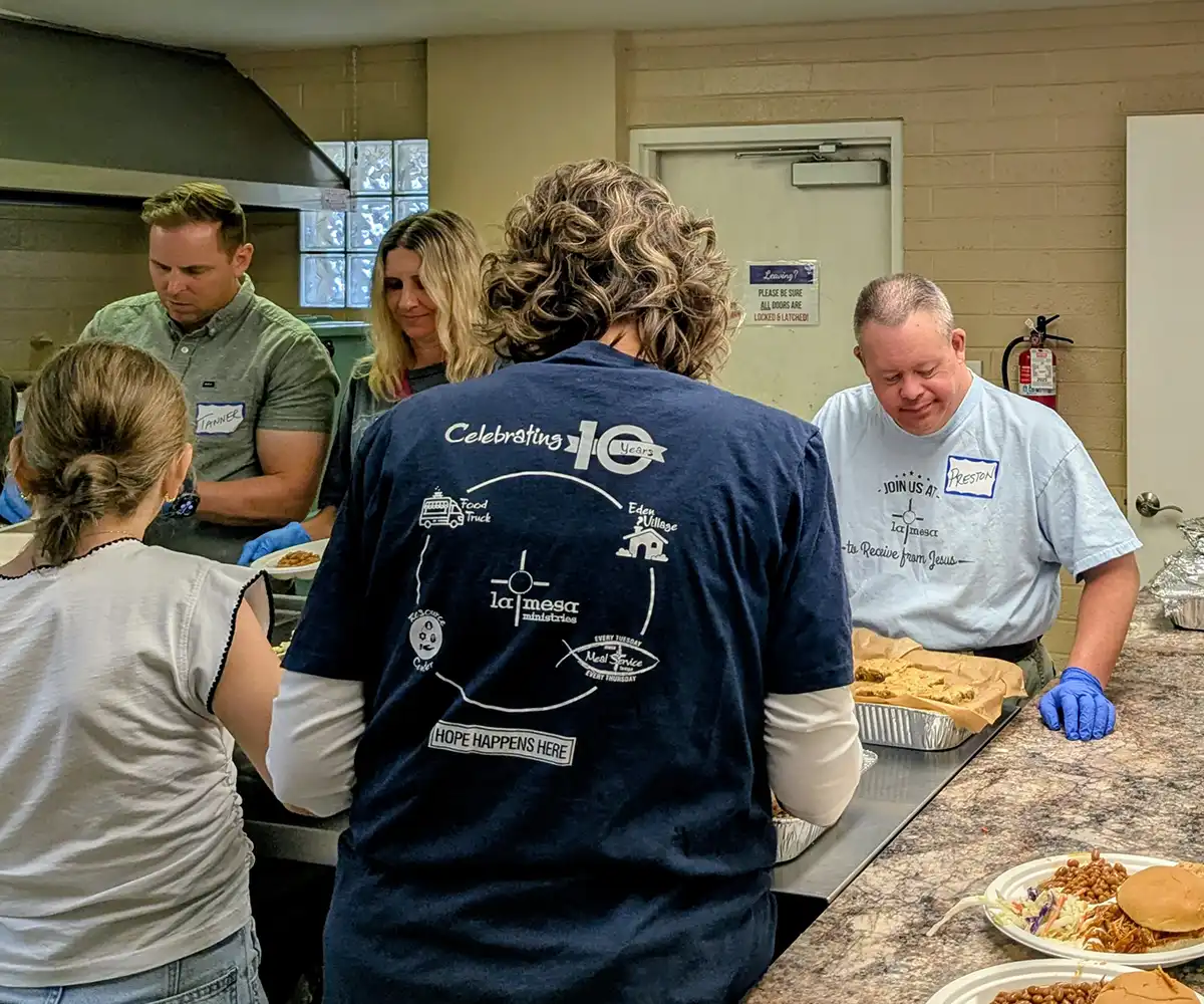 Volunteers preparing and serving meals together during a Prestons Friends outreach event