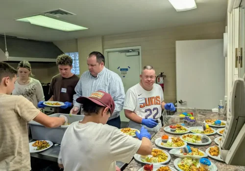 Volunteers preparing and serving meals together during a La Mesa community outreach event
